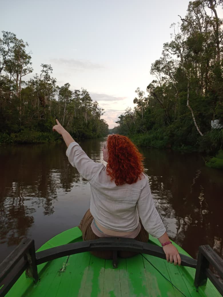 Spotting wildlife from the klotok bow at dusk as the river glows in golden evening light.