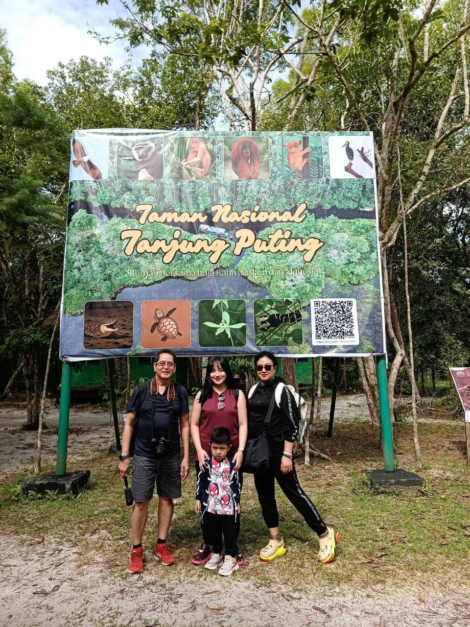 Family photo at the main Taman Nasional Tanjung Puting entrance billboard.