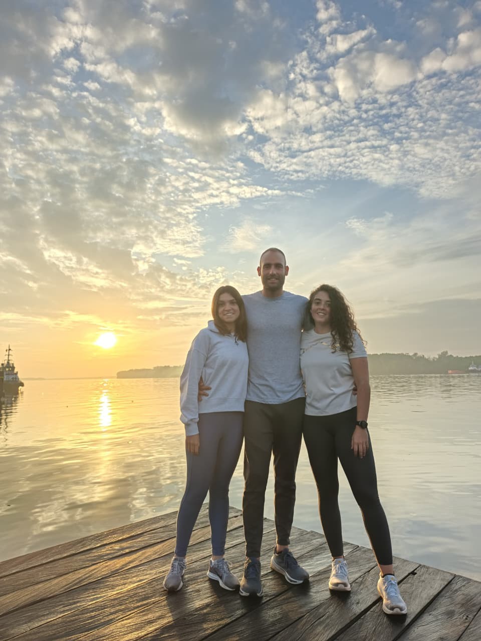 Three guests posing at the riverside dock under a spectacular Borneo sunrise sky.