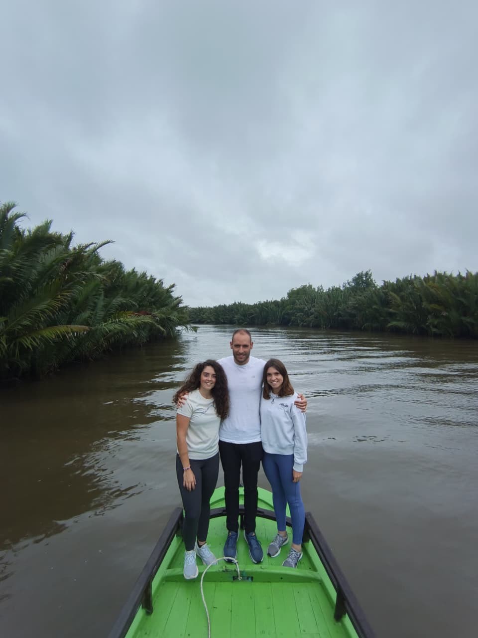 Guests on the front bow of the klotok cruising through nipa palm-lined river channels.